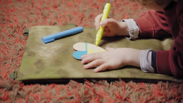 Un enfant peint un cœur aux couleurs du drapeau de l'Ukraine, vue de côté — Video