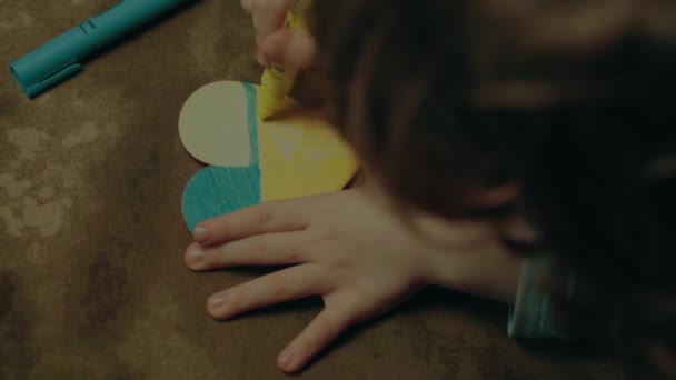 Un enfant peint un cœur aux couleurs du drapeau de l'Ukraine, vue du haut. classement des couleurs — Video