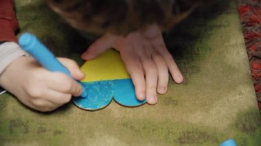 Bir çocuk Ukrayna bayrağının renklerine bir kalp çiziyor, yan görüş, yakın çekim. renk derecelendirmesi