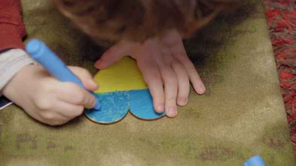 Un enfant peint un cœur aux couleurs du drapeau de l'Ukraine, vue de côté, gros plan — Video