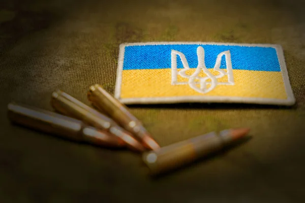 Patch a zászló és a címer Ukrajna, puska patronok egy álcázás háttér. A tapaszra való szelektív összpontosítás — Stock Fotó