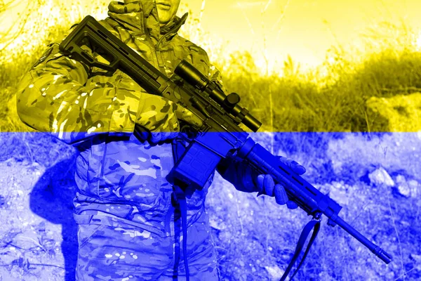 彼の手にライフルを持つウクライナの兵士カモフラージュの制服で。ウクライナの旗の色で描かれ、独立のための闘争の概念 — ストック写真