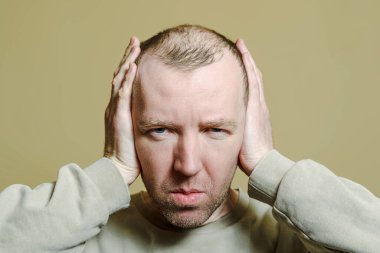 Adam elleriyle kulaklarını kapadı. Surat yapan genç bir adamın portresi