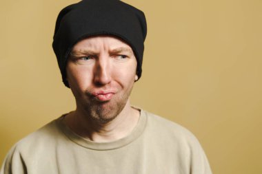 Siyah şapkalı adam küçümseyici görünüyor. Surat yapan genç bir adamın portresi