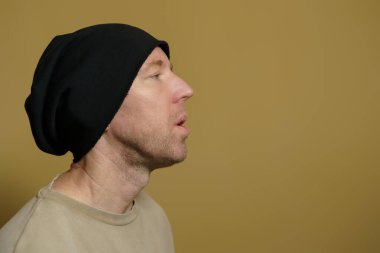 Siyah şapkalı bir adam duman bulutu salıyor. Siyah şapkalı beyaz bir adamın yakın plan portresi.