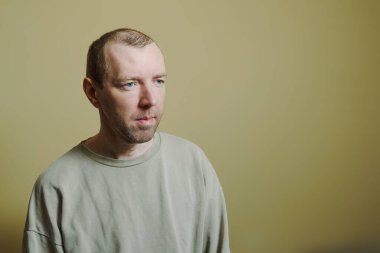 Sarı arka planda gri kazaklı genç bir adamın portresi.