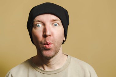 Siyah şapkalı bir adam şaşırmış görünüyor. Surat yapan genç bir adamın portresi.