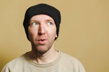 Siyah şapkalı bir adam umutla bakar. Surat yapan genç bir adamın portresi.