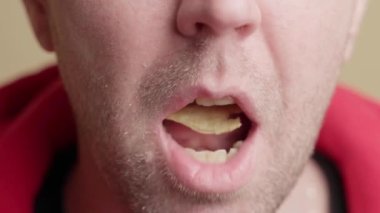 Beyaz adam cips yiyor. Adam ağzına cips koyar ve uzun süre çiğner. Yakın plan, ön görünüm