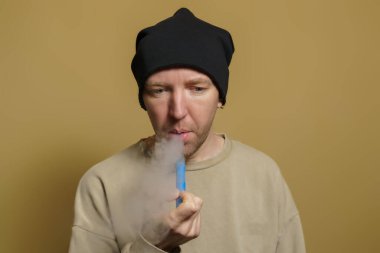 Genç bir Avrupalı adam bir tüp sigara içiyor. Siyah şapkalı beyaz bir adamın portresi..