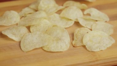 Beyaz adam cips yiyor. Bir adam tahta tabaktan cips seçer. Yakın plan.