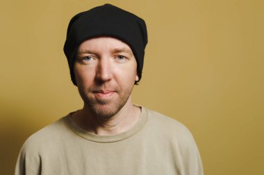 Siyah şapkalı adam ironik görünüyor. Surat yapan genç bir adamın portresi.