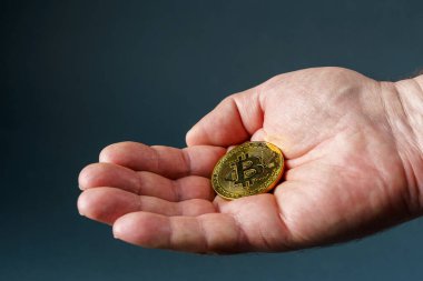 Erkek avucundaki altın bitcoin, yakın plan gri.