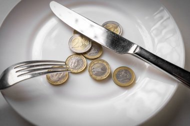 Boş beyaz bir tabakta Euro sikkeleri. Kriz veya yaşam maliyeti sembolü, gıda konsepti fiyatı.