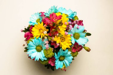 Zarif bir buket sarı ve mavi kasımpatı beyaz bir masada, üst tarafta..