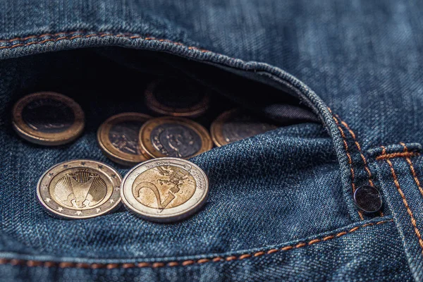Symbol for crisis or cost of living or bankruptcy. Several euro coins in the pocket of old jeans.