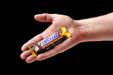 Adamın biri Snickers çikolatası sunuyor, elinde çikolata, yakın plan, siyah arka plan..