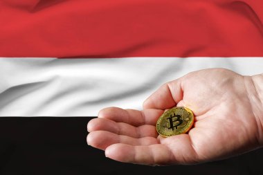 Altın Bitcoin bir adamın elinde, arka planda Yemen bayrağı.