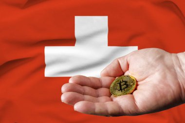 Altın para adamın elinde, İsviçre bayrağı da arka planda..