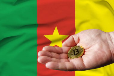 Altın para adamın elinde, Kamerun bayrağı da arka planda..