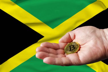 Altın para adamın elinde, Jamaika bayrağı da arka planda..