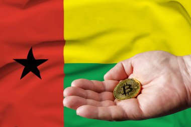 Altın Bitcoin bir adamın elinde, arka planda Gine-Bissau bayrağı.