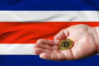 Altın para adamın elinde, Kosta Rika bayrağı da arka planda..