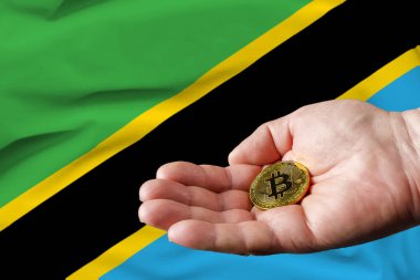 Altın Bitcoin erkekler elinde, Tanzanya bayrağı arka planda.