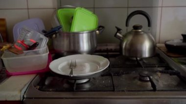 Dirty dishes in the kitchen and stove. Unwashed spoons, forks, pots.