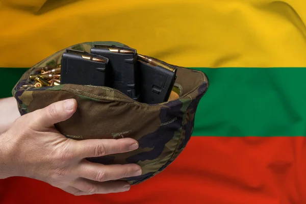 在立陶宛国旗的背景下 一个手拿步枪弹夹和弹夹的军事头盔 出售武器或军事援助的概念 — 图库照片
