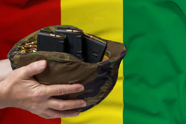 在几内亚国旗的背景下 一个手拿步枪弹夹和弹夹的军事头盔 出售武器或军事援助的概念 — 图库照片