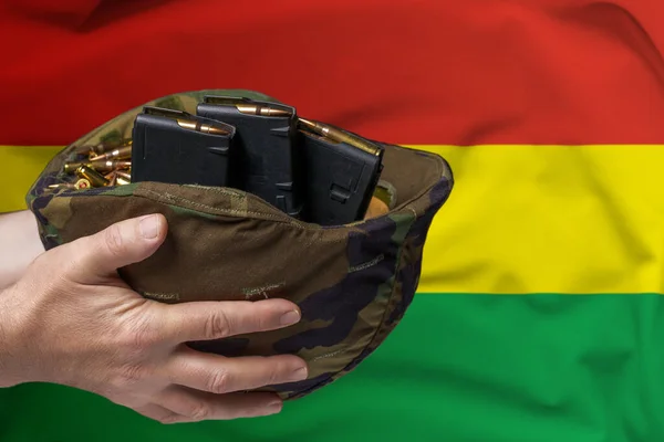 在加纳国旗的背景下 一个手拿步枪弹夹和弹夹的军事头盔 出售武器或军事援助的概念 — 图库照片