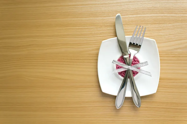 White plate with fork and knife on a wooden table — Stock Photo, Image