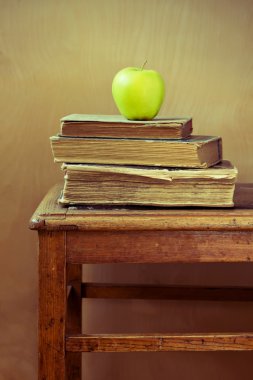 stapelen van oude boeken en groene appel op oude stoel