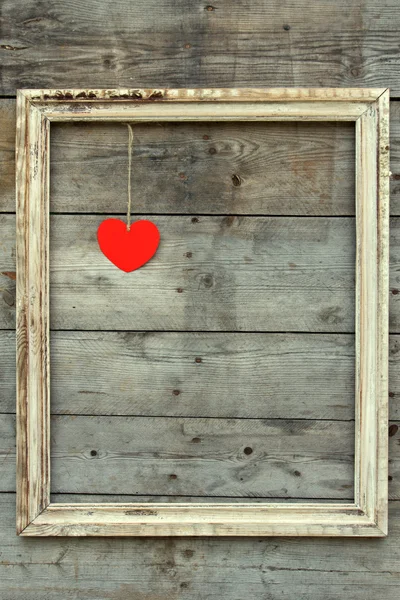 Moldura de madeira vintage com coração vermelho em um fundo grunge — Fotografia de Stock
