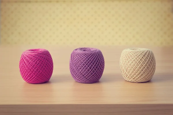 Balls of threads on a wooden table over vintage wallpaper — Stock Photo, Image