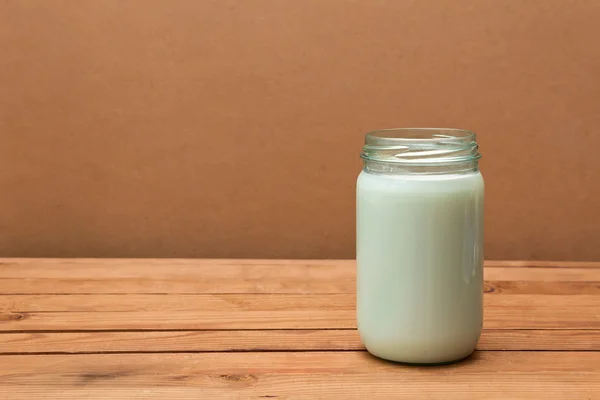 Öppna glasburk med färsk mjölk på ett träbord — Stockfoto