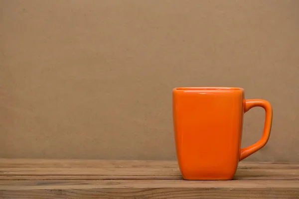 Orange mug on wooden table — Stock Photo, Image