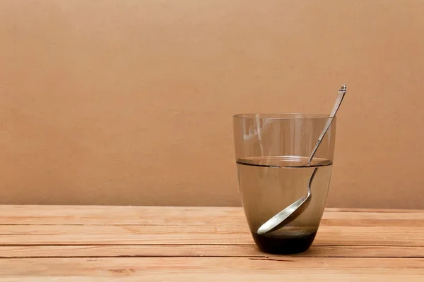 Glas vatten och sked på träbord. — Stockfoto