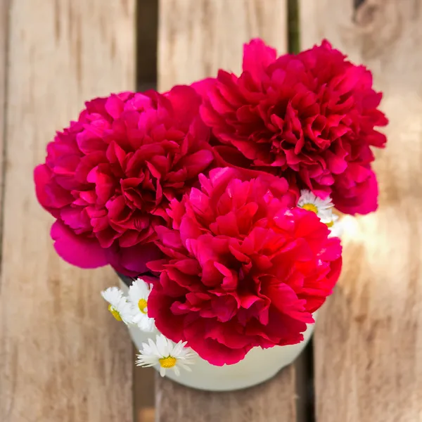 Red peonies in vase on wood background — Stock Photo, Image