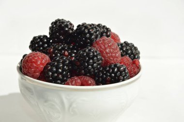 Olgun, taze meyveler. Beyaz arka planda ahududu ve böğürtlen. Vitamin tatlısı.