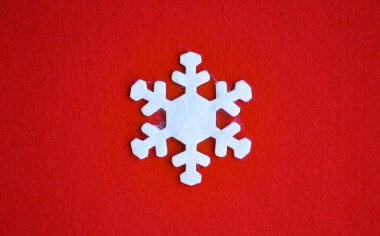 Kırmızı zemin üzerinde beyaz keçeli kar taneleri. Noel ve Yeni Yıl için dekorasyon. Kış tatili.