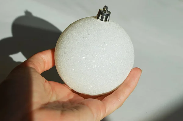 Μια Άσπρη Λαμπερή Χριστουγεννιάτικη Μπάλα Στο Χέρι Του Διακόσμηση Για — Φωτογραφία Αρχείου