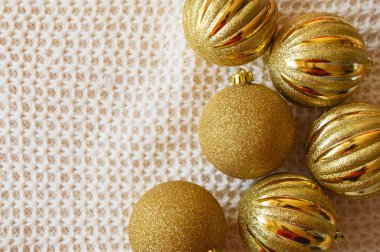 Noel ağacı için parlak altın toplar örülmüş beyaz bir battaniyenin üzerinde. Noel ve Yeni Yıl için dekorasyon arkaplanı.