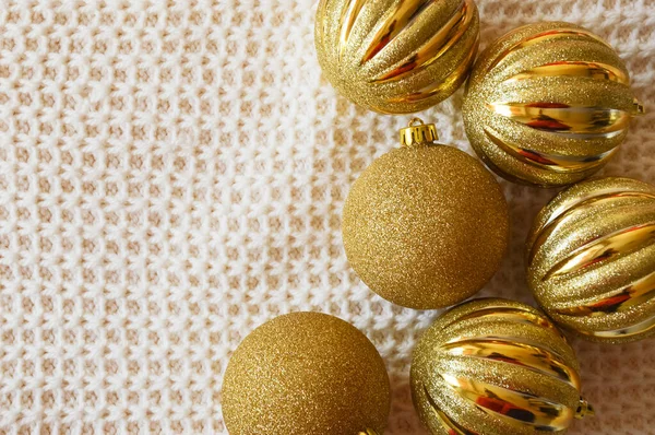 Noel ağacı için parlak altın toplar örülmüş beyaz bir battaniyenin üzerinde. Noel ve Yeni Yıl için dekorasyon arkaplanı.