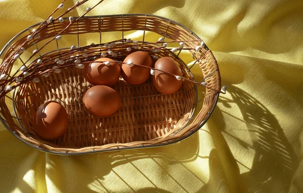 ハッピーイースター 春の休日のための美しい装飾 太陽の光の下で黄色の背景にウィッカーバスケットの鶏の卵 — ストック写真