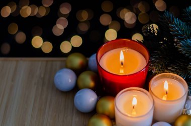 Odaklan ve bulanık mumları ahşap tepsiye koy. Noel ağacı ve arka planda bokeh ışığı olan süsler koy..