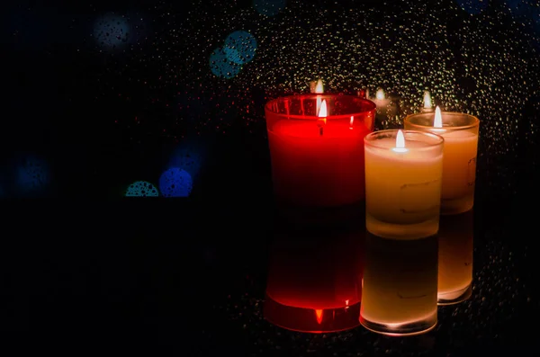 Fokus Und Verschwommene Brennende Kerzen Neben Regentropfen Auf Fenster Dunklen — Stockfoto