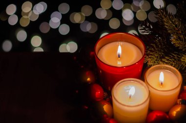 Noel ağacıyla yanan mumlara odaklan ve bulanıklaştır. Bokeh ışığı ve karanlık arkaplan üzerine takılar tak..