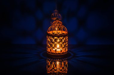 Kutsal Ramazan Kareem bayramı için mavi arkaplandan yansıyan altın fenerin seçici odak noktası.